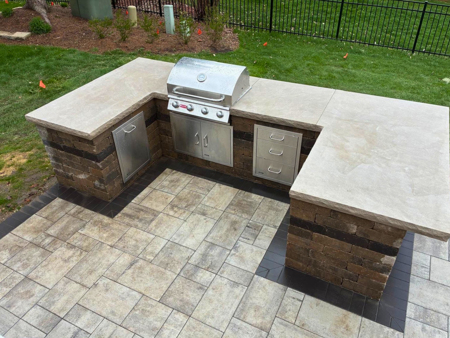 custom outdoor kitchen with grill, drawers, and limestone counter top.